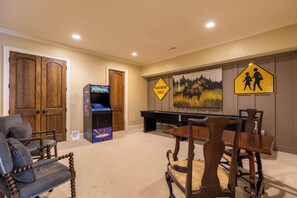 A living room with a pool table, a wooden cabinet, a gaming console, and a dining area with a table and chairs. - Fern Ridge Lodge at Sweetgrass (Blowing Rock)
