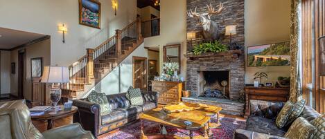 A spacious living room with a fireplace, leather sofas, a wooden coffee table, and a staircase leading to an upper level.