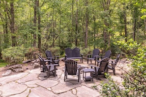 A stone patio with Adirondack chairs arranged for outdoor dining. - Fern Ridge Lodge at Sweetgrass (Blowing Rock)