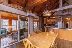 L’intérieur d’un chalet rustique est doté d’une table à manger en bois, de chaises et d’un coin cuisine avec des armoires et des appareils électroménagers en bois.