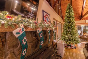 Une pièce chaleureuse avec une cheminée, un sapin de Noël et des décorations festives.