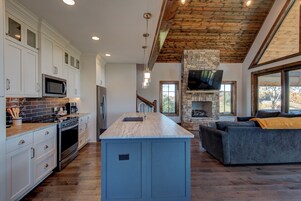 Una cocina moderna con gabinetes blancos, una isla central y una chimenea de piedra.