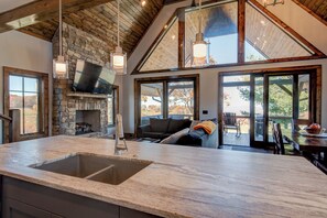 Una cocina amplia con chimenea de piedra, ventanas grandes y un techo alto con vigas de madera.