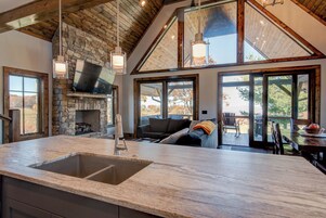 Una cocina amplia con chimenea de piedra, ventanas grandes y un techo alto con vigas de madera.