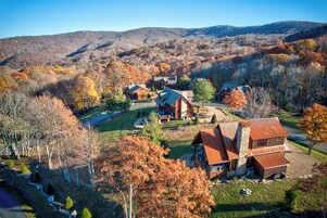 A lodge with multiple cabins, surrounded by autumn foliage and hills.