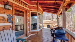 Eine Holzhütte mit Veranda, Grill und einer Willkommensschild.