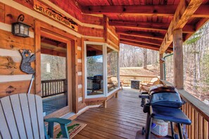 Eine Holzhütte mit Veranda, Grill und einer Willkommensschild.