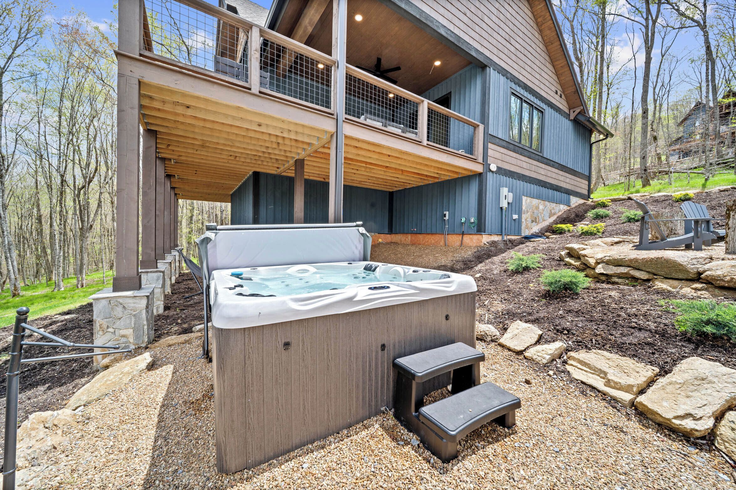 A modern house with a hot tub, wooden deck, and stone steps.