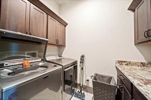 Eine kleine Küche mit Edelstahlgeräten, Holzschränken und einer Arbeitsplatte aus Granit.