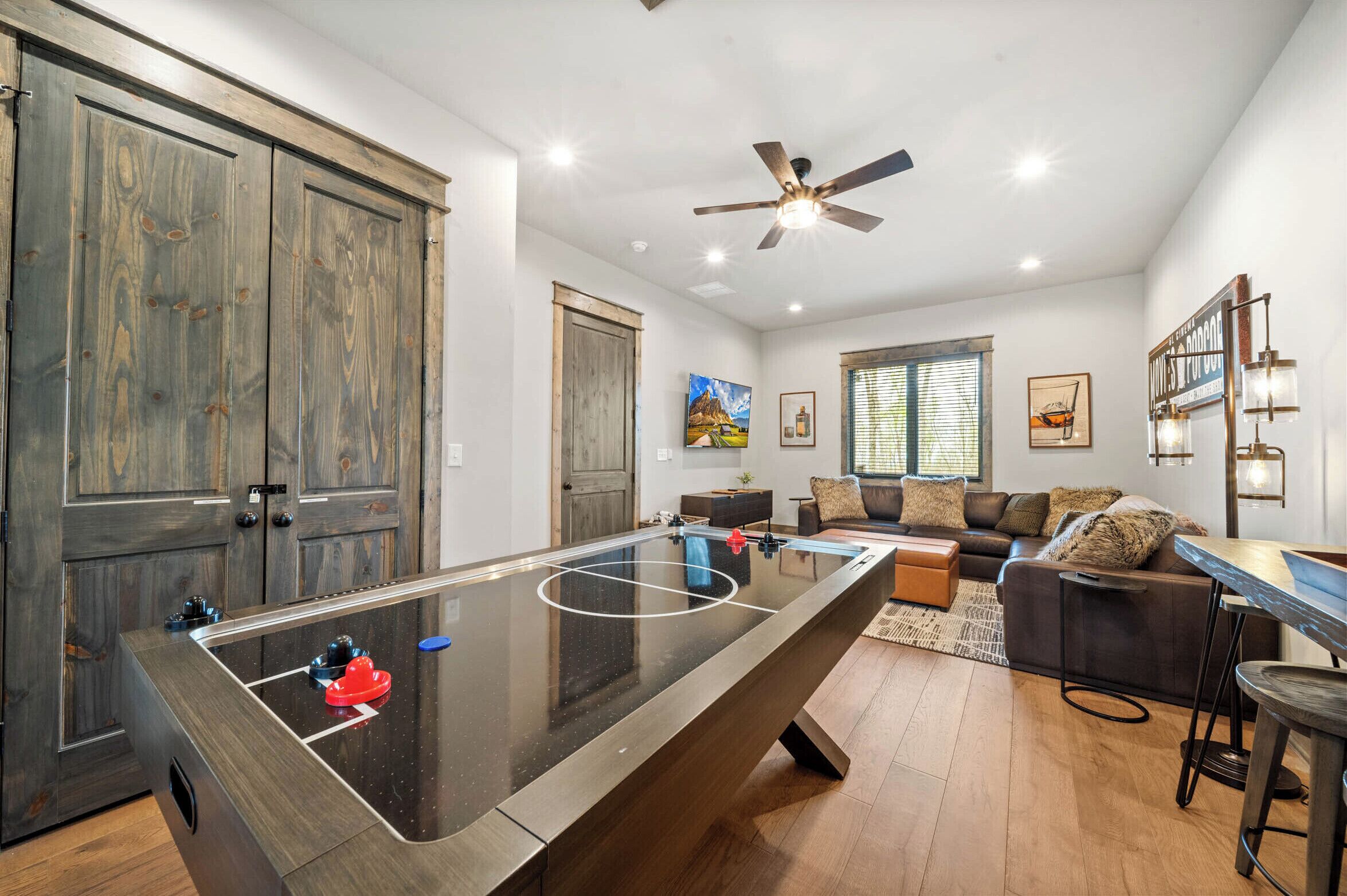 A spacious living area with a foosball table, a ceiling fan, and a large wooden door.