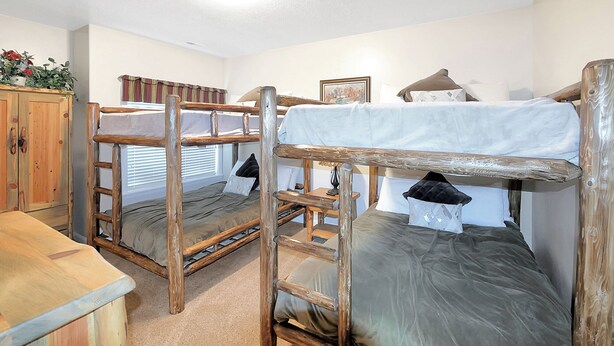 A bunk bed room with a wooden ladder, a small table, and a window with blinds. - 6486 Lakeside #15 (Huntsville)