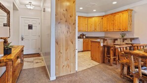 A kitchen with wooden cabinets, a dining area with a wooden table and chairs, and a white door with a sign. - 6486 Lakeside #15 (Huntsville)