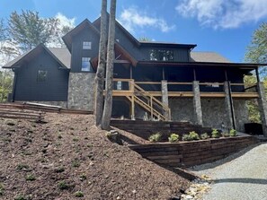 Ein zweistöckiges Haus mit einer Steinaußenwand, einer Holzterrasse und einer Steinsichtmauer.