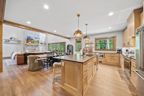 A spacious kitchen with wooden cabinets, a central island, and a dining area with a bench. - Sweet Bearadise at Eagles Nest (Banner Elk)