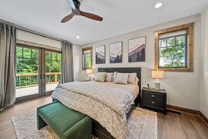 Ein Schlafzimmer mit Bett, Nachttisch, Deckenventilator und Blick ins Freie.