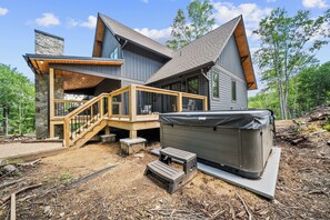A modern cabin with a stone facade, a wooden deck, and a hot tub. - Sweet Bearadise at Eagles Nest (Banner Elk)