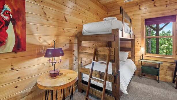 Ein Zimmer in einer Holzhütte mit Etagenbetten, einem Tisch mit einer Lampe und einem Bild an der Wand.