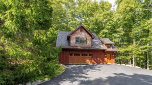 A wooden cabin with a garage, surrounded by dense forest. - Matney Ridge Estate (Banner Elk)