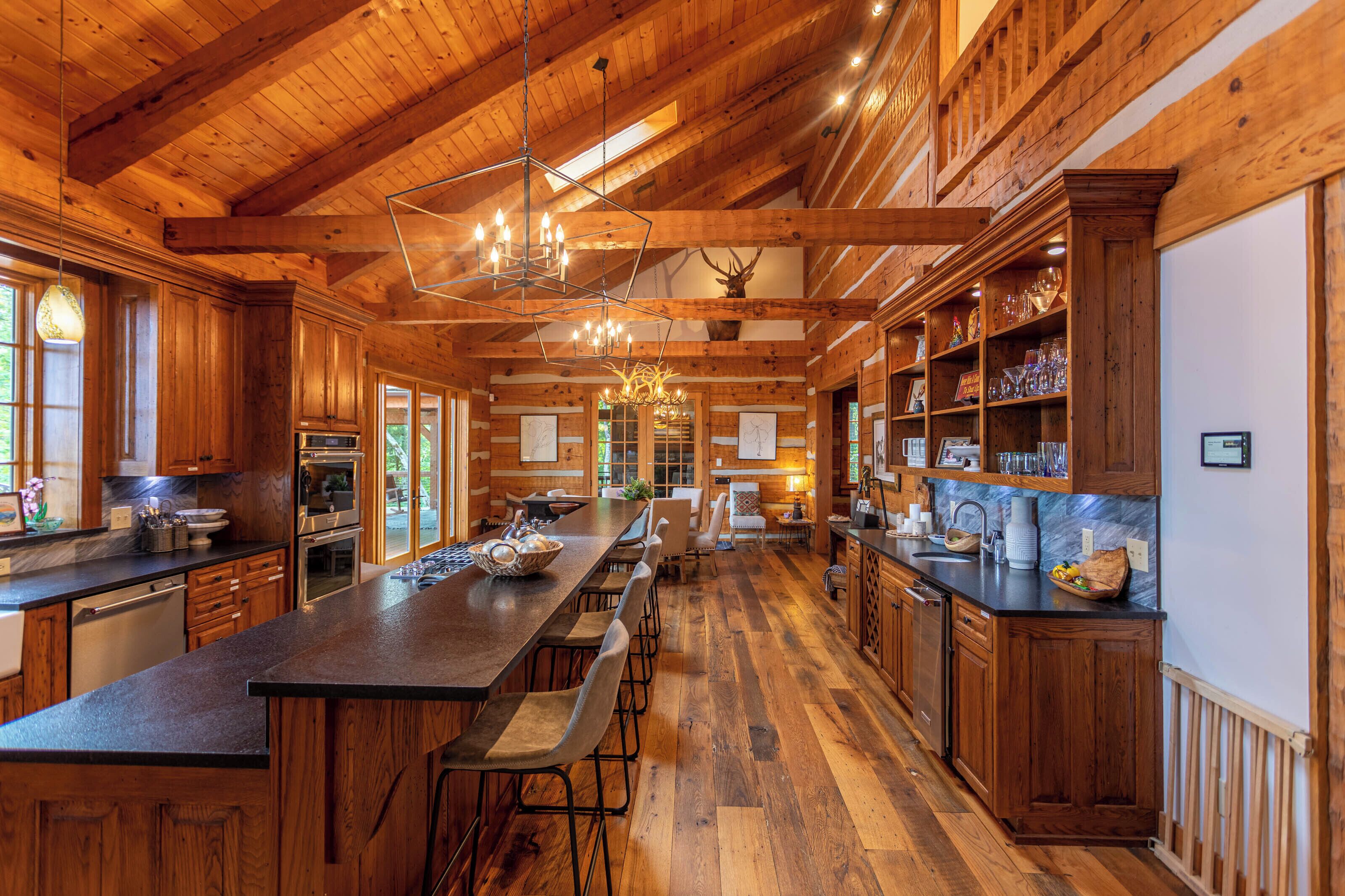 Une cuisine spacieuse avec des meubles de rangement en bois, un grand îlot central doté de tabourets et un lustre.