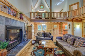 A spacious log cabin interior with a fireplace, a wooden balcony, and a cozy seating area. - Hideaway Homestead (Banner Elk)