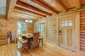 A log cabin interior with a dining area, wooden walls, and a large window. - Hideaway Homestead (Banner Elk)