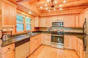 A modern kitchen with wooden cabinets, a stainless steel oven, a microwave, and a dishwasher. - Hideaway Homestead (Banner Elk)
