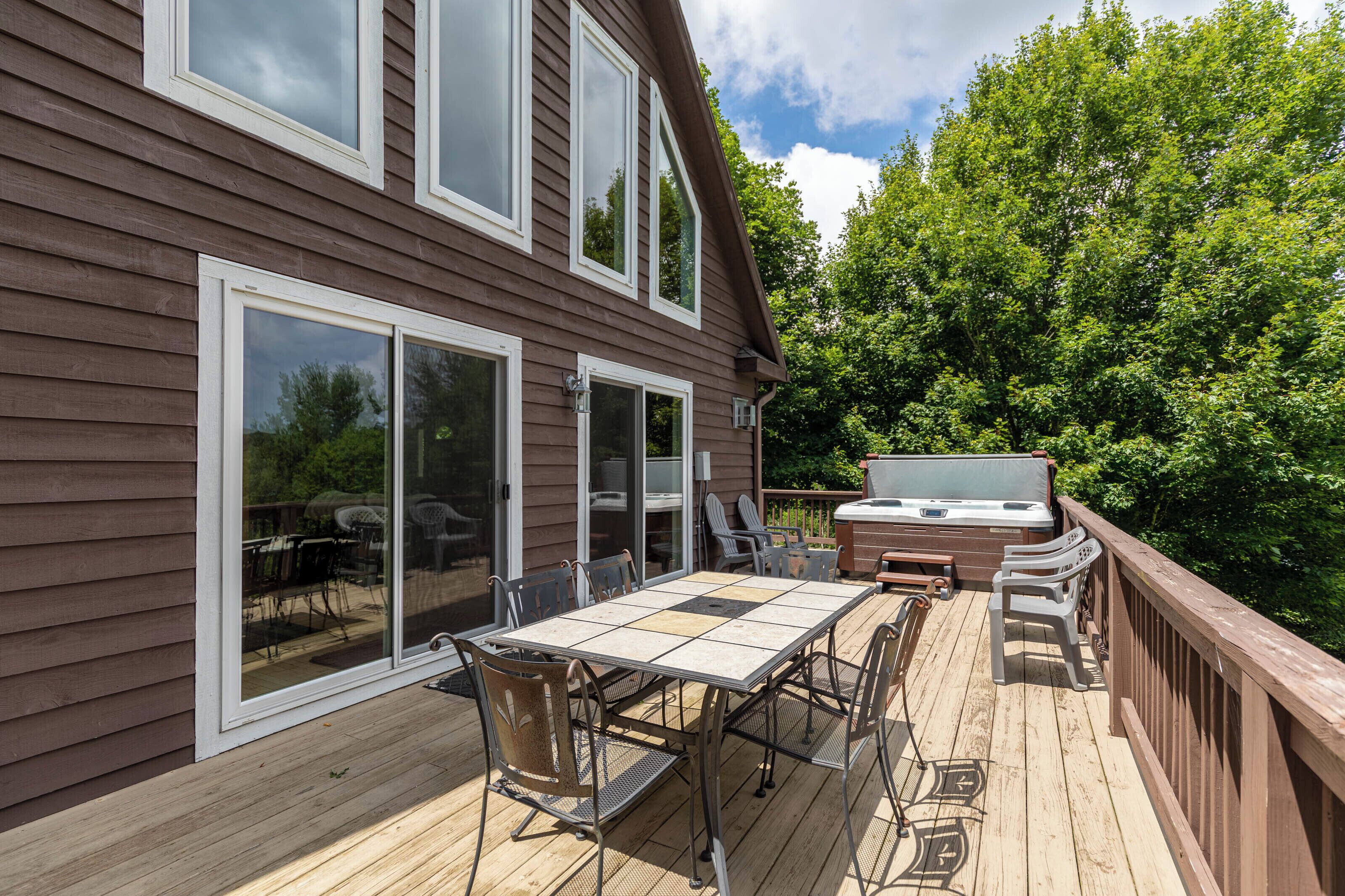 A deck with a table and chairs, a grill, and a sliding glass door.