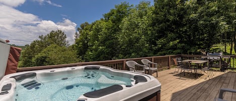 Un bain à remous sur une terrasse en bois, avec un barbecue et du mobilier d’extérieur.