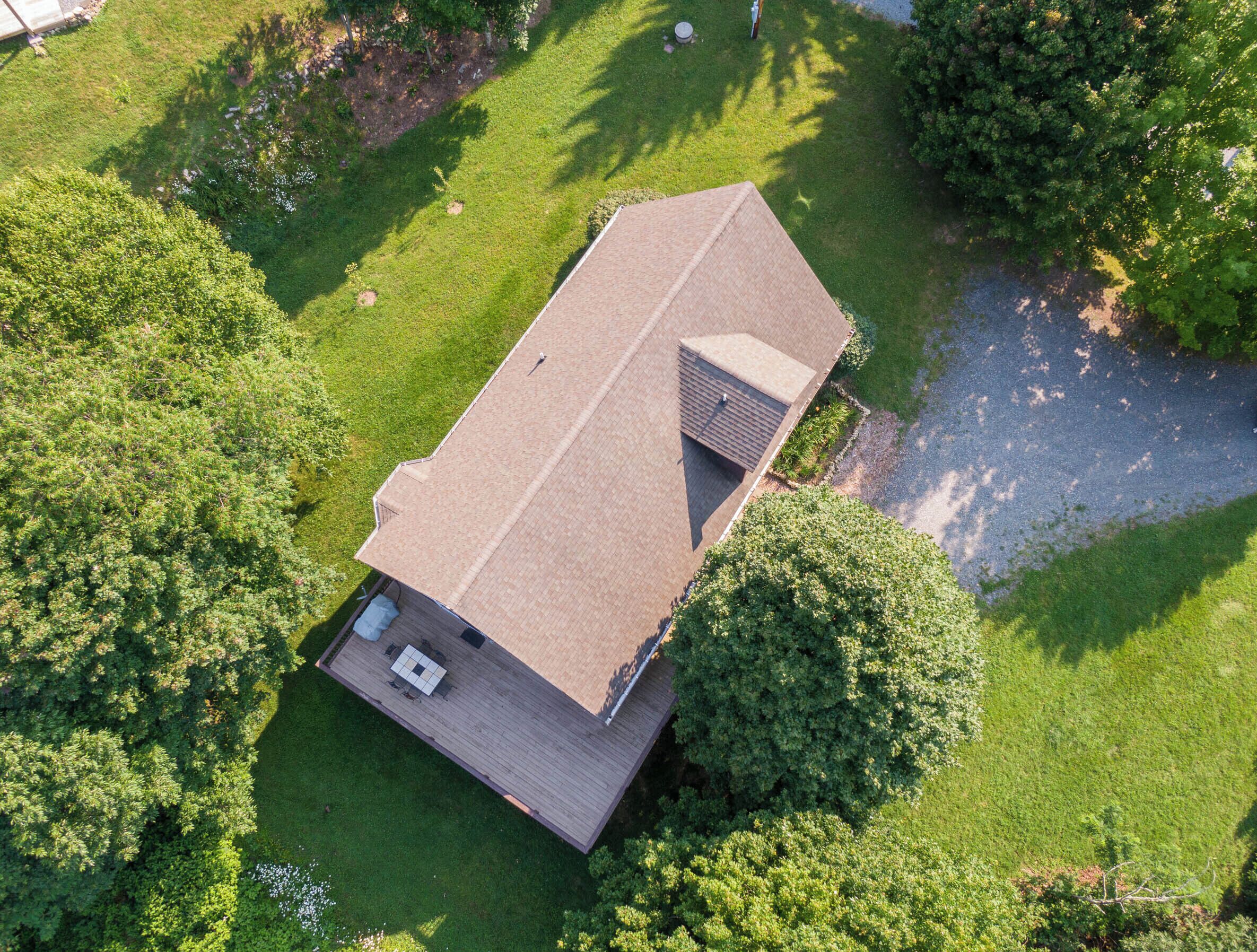 An aerial view of a house with a sloped roof, a deck, and a small garden area.