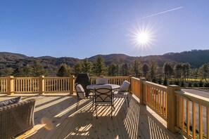 A wooden deck with outdoor furniture, a grill, and a view of a hilly landscape. - Valley View (Banner Elk)