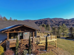 A cabin with a covered porch, a deck, and a view of the surrounding mountains. - Valley View (Banner Elk)