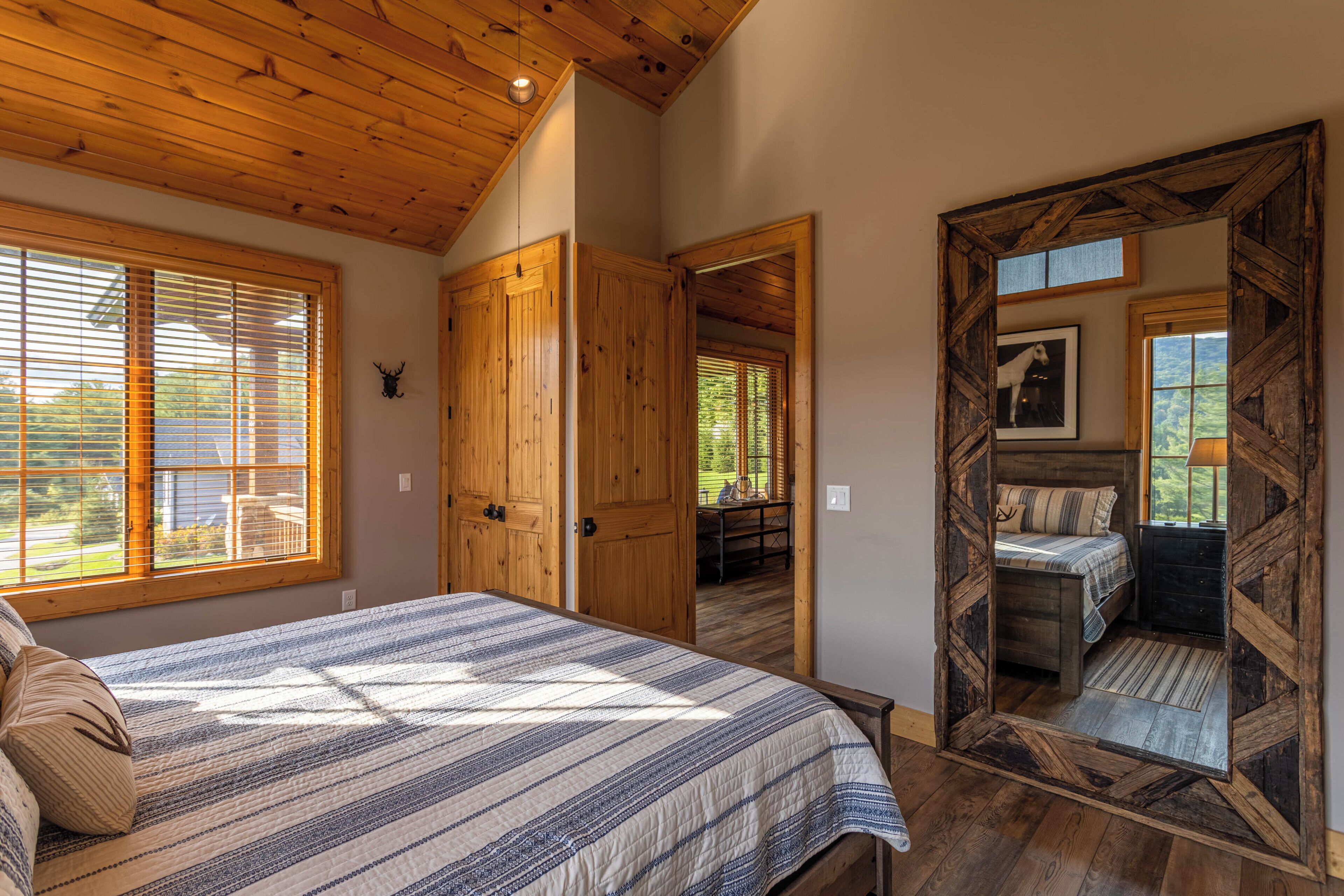 A bedroom with a large bed, wooden ceiling, and a view of a balcony.