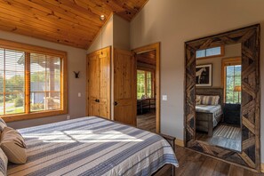 A bedroom with a large bed, wooden ceiling, and a view of a balcony. - Valley View (Banner Elk)