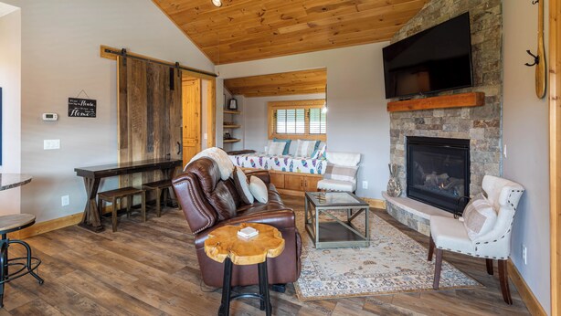 A cozy living room with a stone fireplace, wooden ceiling, and a comfortable seating area. - Valley View (Banner Elk)