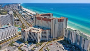 A high-rise hotel with multiple floors, a parking lot, and a beachfront view. - Shores of Panama 1323 (Panama City Beach)