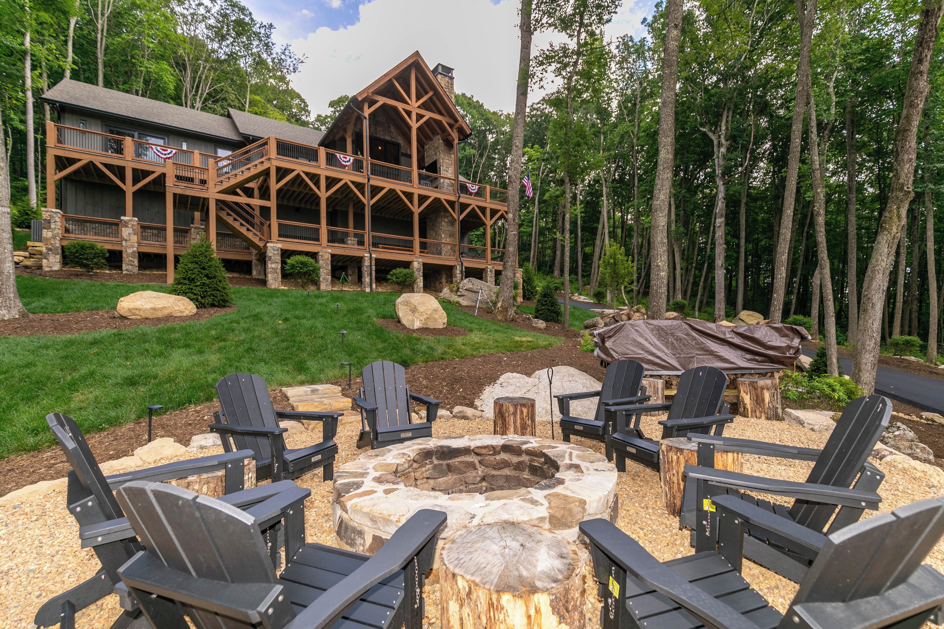 A lodge with a stone fire pit and Adirondack chairs.