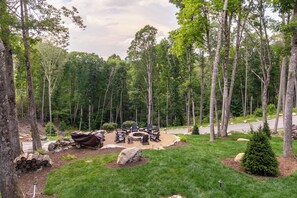 A forested campsite with a fire pit and seating area. - On Mountain Time at Eagles Nest (Banner Elk)