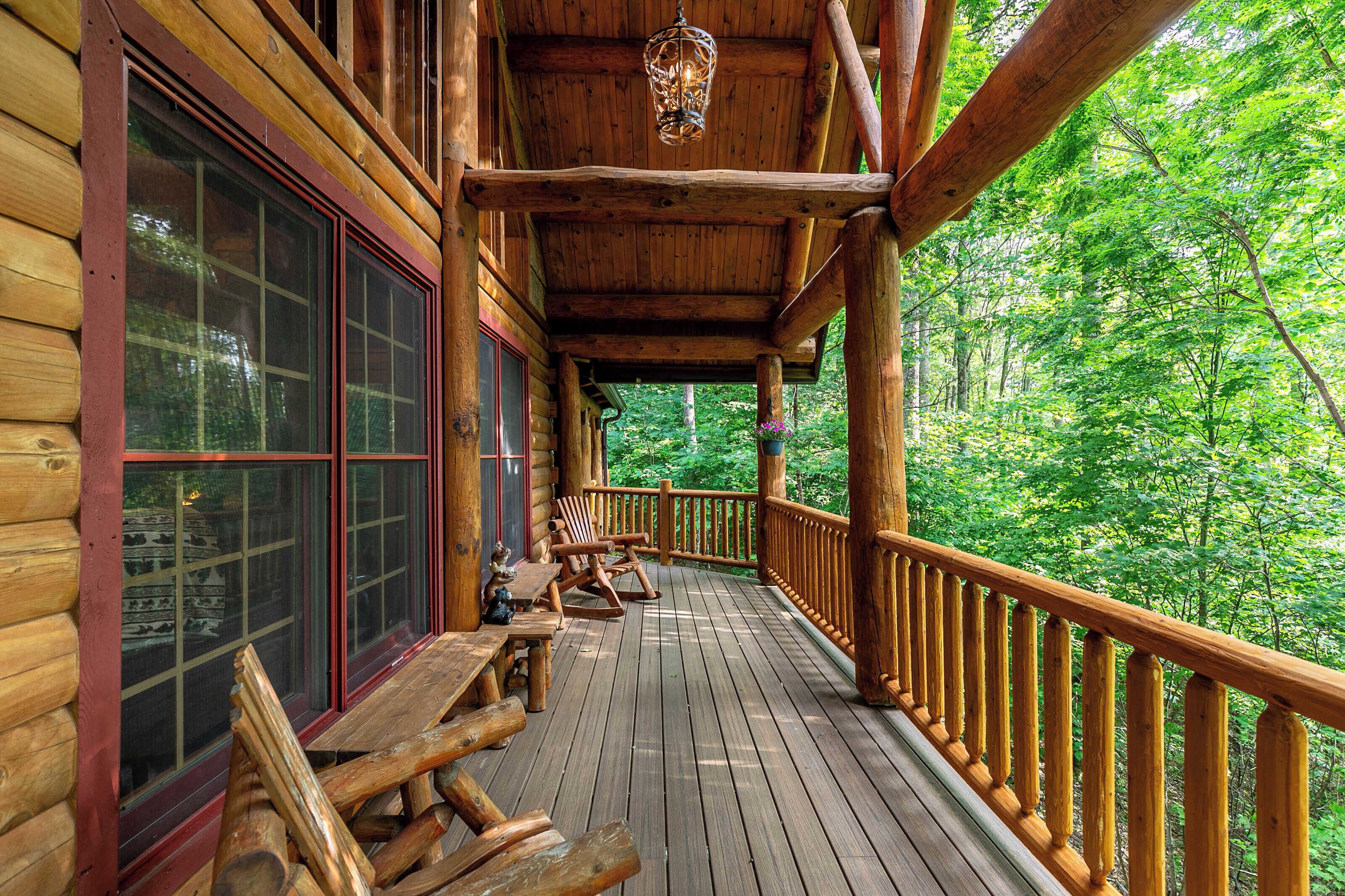 Une terrasse en bois avec une rambarde, des bancs en bois et un luminaire suspendu.