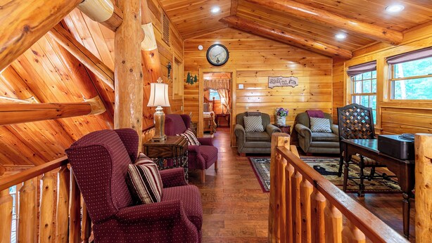 A cozy cabin interior with wooden walls, a wooden ceiling, a clock, and a sign reading "Cabin's Bliss." - 4BR Running Waters Lodge at Eagles Nest (Banner Elk)