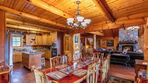 A log cabin interior with a wooden dining area, kitchen, and living room. - 4BR Running Waters Lodge at Eagles Nest (Banner Elk)