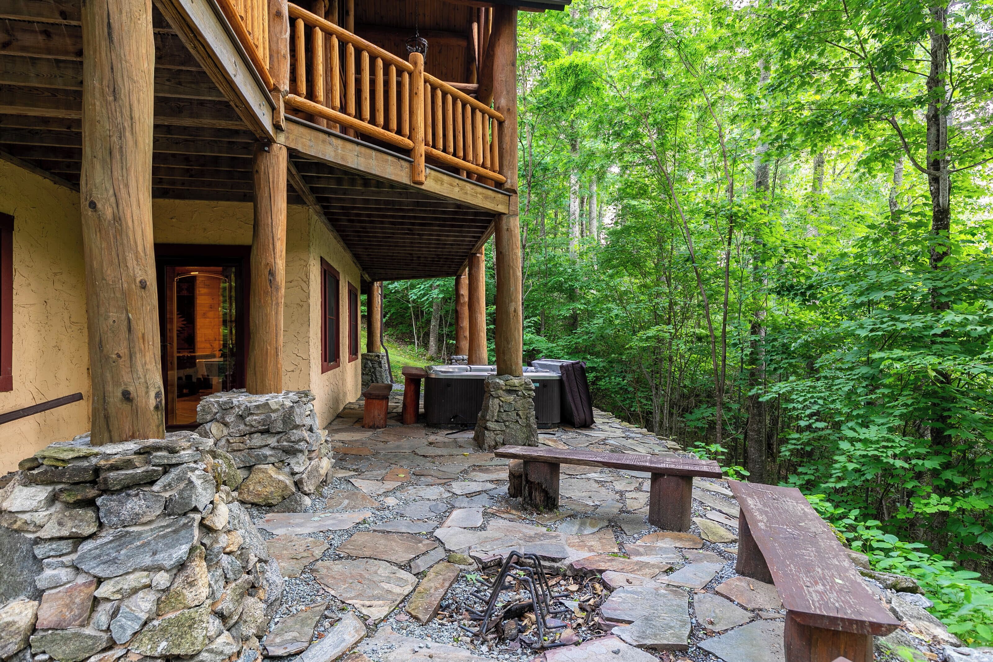 A rustic cabin with a stone patio, outdoor seating, and a fire pit.