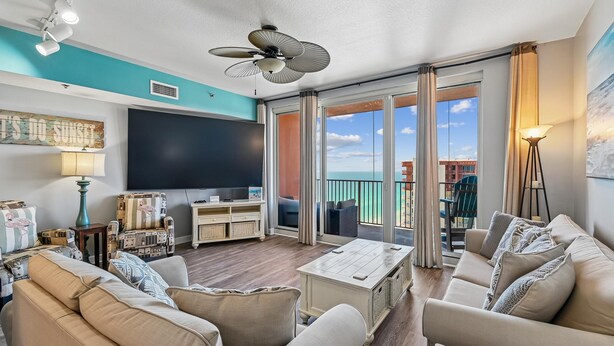 A living room with a flat-screen TV, sofas, a coffee table, and a balcony with a view. - Shores of Panama 2326 (Panama City Beach)