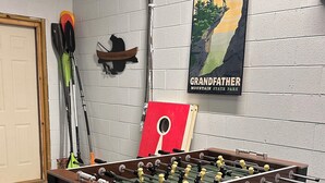 Ein Kicker steht in einem Raum mit weißer Ziegelwand, einem Poster vom Grandfather Mountain in North Carolina und mehreren Angelausrüsten.