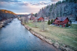 Ein Fluss fließt durch eine ländliche Gegend mit zwei roten Holzhütten.