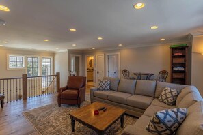 A spacious living room with a sofa, armchairs, a coffee table, and a bookshelf.