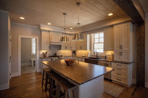A spacious kitchen with wooden cabinets, a large island, and pendant lighting.