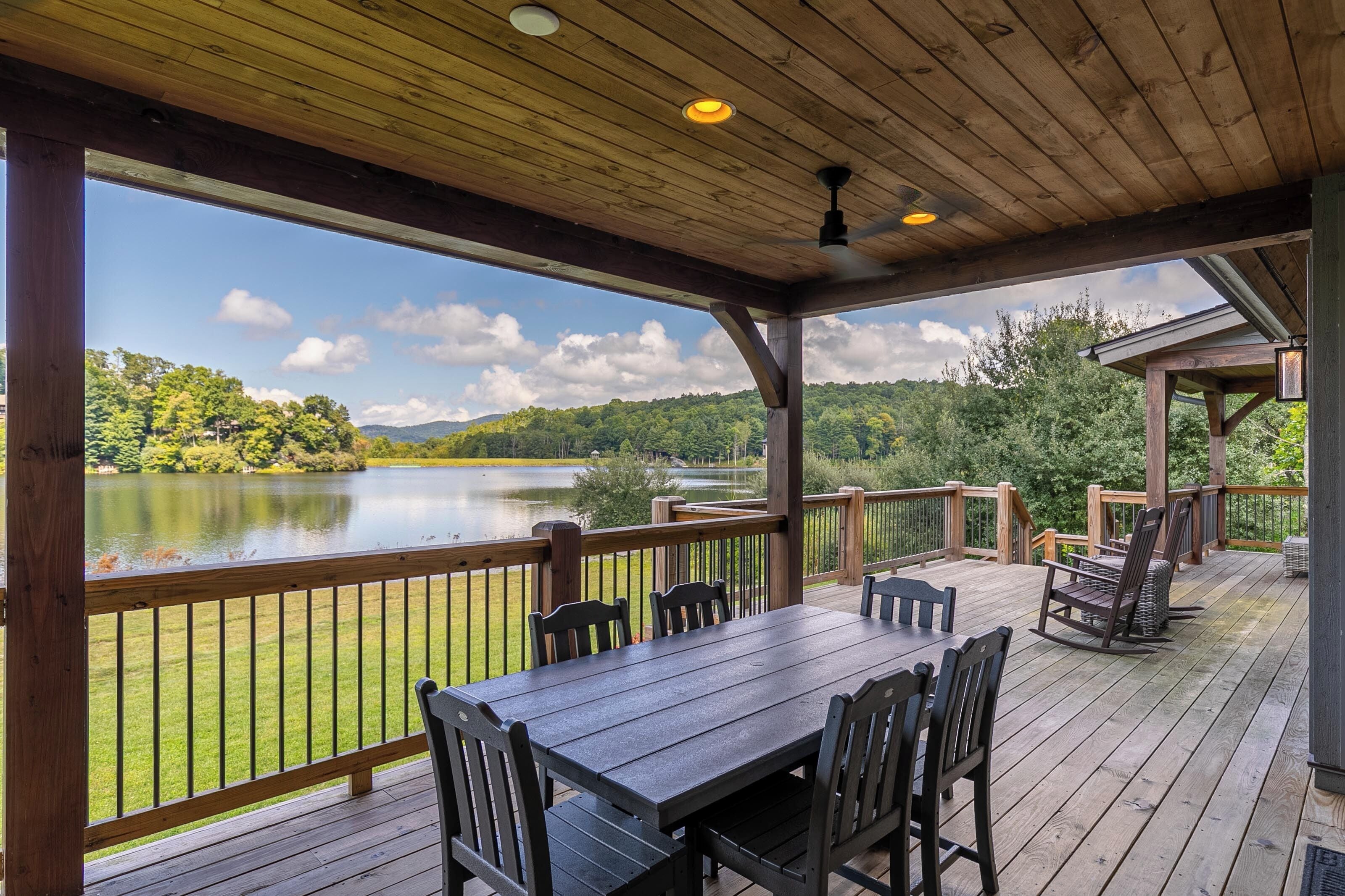 A wooden deck with a table and chairs overlooking a lake.