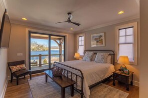 A bedroom with a large bed, a bench, a desk, and a view of the outdoors. - Lakeshore Retreat at Sweetgrass (Blowing Rock)