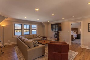 A spacious living room with a sofa, coffee table, and a TV mounted on the wall.
