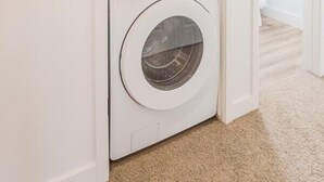 Una sala de lavandería con dos lavadoras de carga frontal apiladas.